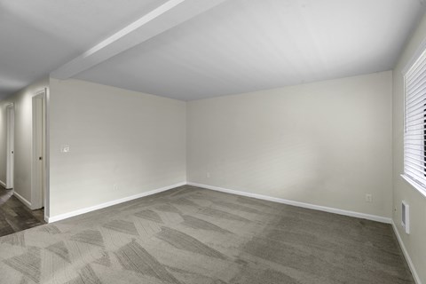 the living room of a manufactured home with a gray carpet and white walls